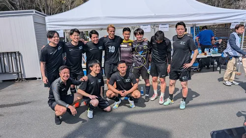 Group photo from the futsal tournament. Participants in kit in front of a tent.