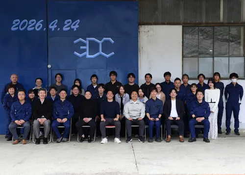 Group photo from the company offsite. Members from every site lined up in front of the 3DC logo.