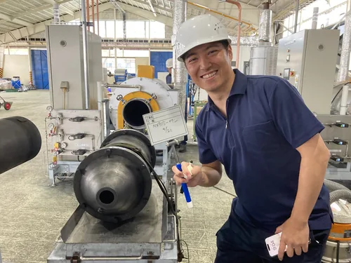 A research and production workshop. A member in a helmet working in front of equipment.
