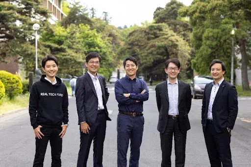 Members at the Sendai head office. Five people standing on a road on the Tohoku University campus.